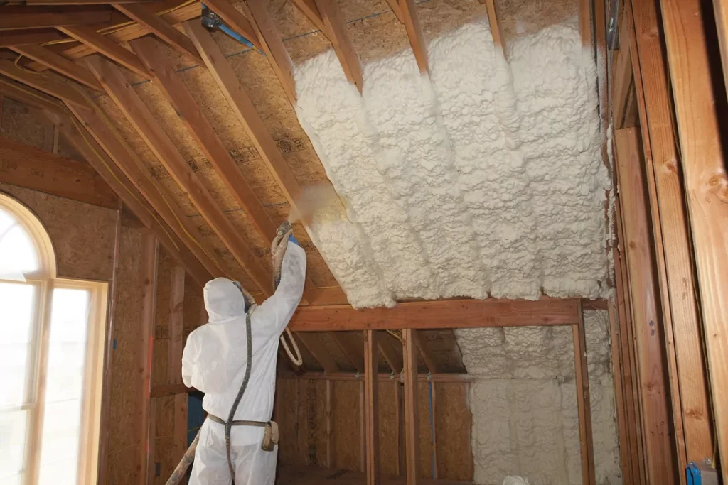 A contractor fully equipped applying spray foam to the roof.